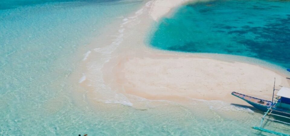 A photo of Manukan Island beach at Kota Kinabalu, Sabah, with white sand, blue water and green hills.