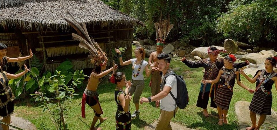 A group of tourists wearing traditional costumes and dancing with the local performers at Mari-Mari Cultural Village, a cultural attraction in Sabah that showcases the history and lifestyle of five ethnic tribes.