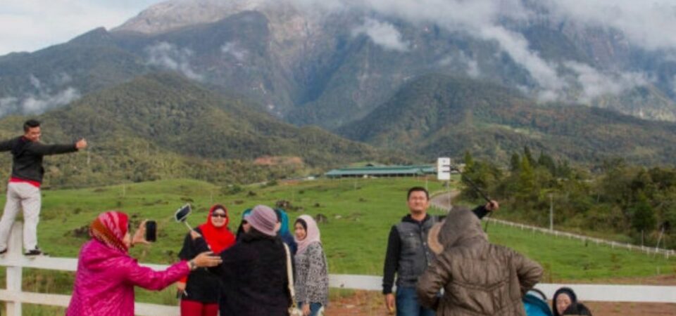 A group photo at Desa Cattle Dairy Farm, Kundasang, Sabah, with a sign that says “Desa Cattle Dairy Farm” and a cow logo, and a view of Mount Kinabalu in the background.