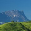 A scenic view of Mount Kinabalu peak with clouds and greenery