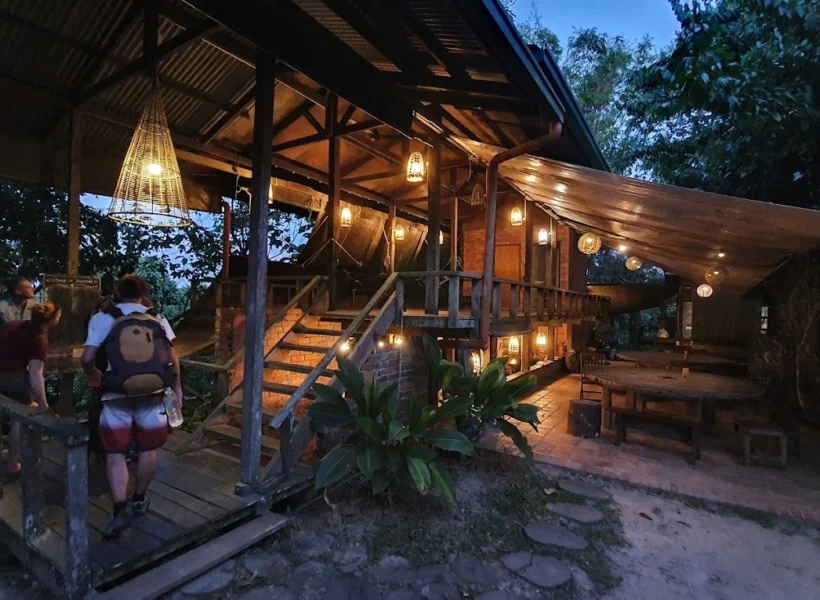 Night view of Paganakan Dii Eco Lodge in Sandakan, softly lit amid lush rainforest surroundings.