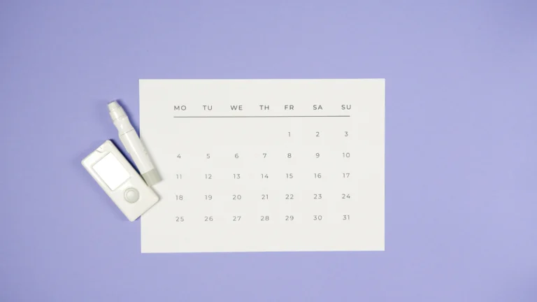 calendar placed on a table, with a marker and music player next to it